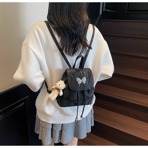 Detail of black backpack with silver butterfly clasp and plush bear charm decoration