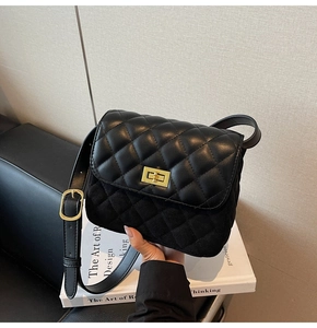 Detail of black quilted chain bag with gold rectangular turn-lock and leather strap