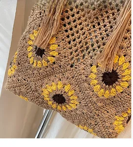 Detailed close-up of handmade straw bag featuring crochet sunflower pattern and long tassels