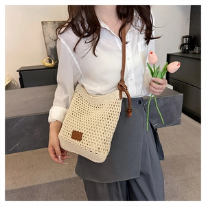 Detail of hollow woven tote bag featuring beaded brown leather straps and beige mesh texture