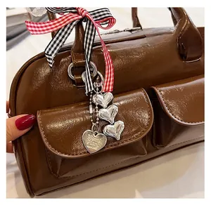 Detailed close-up of brown shiny leather bag with heart charms and plaid ribbon bow