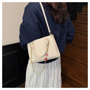 Détail du sac cabas blanc crème avec texture litchi et breloque chaîne fraise rouge