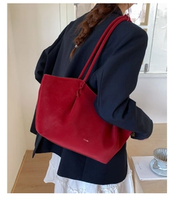 Détail du cabas en daim rouge avec logo CLEAR et bretelles nouées sur le mannequin