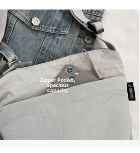 Dettaglio della borsa a tracolla in nylon grigio chiaro con tasca frontale con zip