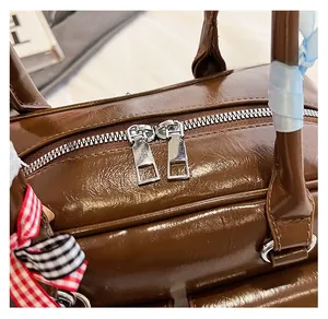 Detail view of smooth silver-tone double zippers on a vintage brown leather bowling bag
