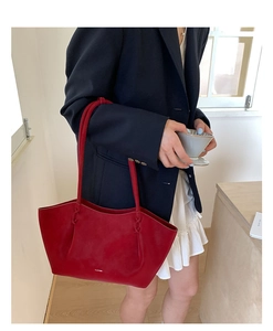 Détail du sac cabas rouge avec poignée à nœud et logo blanc porté par un mannequin