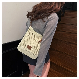 Detailed view of cream crochet weave texture and brown leather logo tag on tote bag