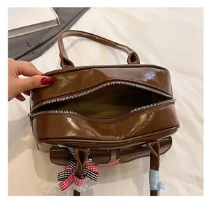 Detail view of coffee brown patent leather bowling bag with interior storage and ribbon