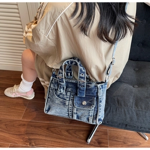Lifestyle shot of washed blue denim tote bag with metal buckles and small front flap pocket