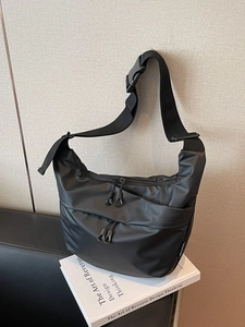 Minimalist black nylon crossbody bag with dual front zippers and wide woven shoulder strap