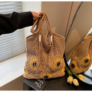 Detailed macro of handmade sunflower straw tote bag featuring woven tassels and boho style