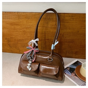 Close-up of dark brown patent leather shoulder bag with decorative bows and metal charms
