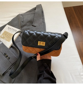 Detailed view of bicolor quilted crossbody bag with gold hardware held in hand