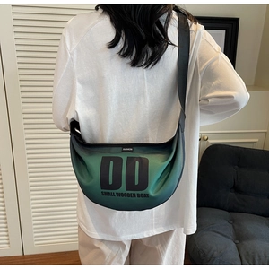 Detail view of a green gradient nylon crescent bag with black letter print and adjustable strap