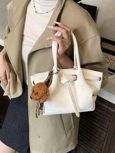 Sac seau beige tendance avec pendentif ours porté par un mannequin en costume