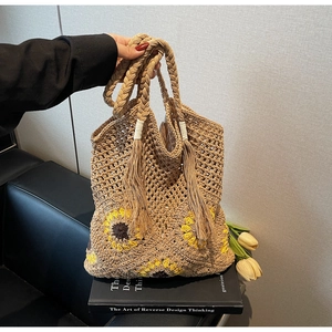 Detail of hand-woven straw shoulder bag featuring sunflower pattern and tassel handle