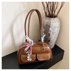 Close-up of retro brown shoulder bag with silver heart charms and checkered ribbon detail