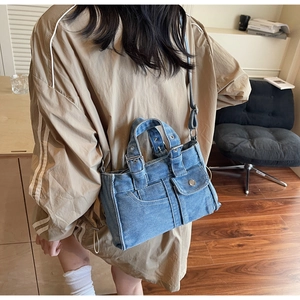 Detail view of a vintage denim shoulder bag with metal rivets and stylish buckle details