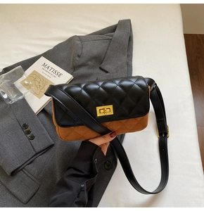 Detail view of two-tone quilted shoulder bag with gold turn-lock on grey blazer