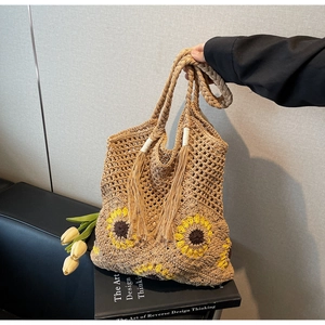 Detail of handmade straw bag with sunflower motif and long tassels for summer leisure