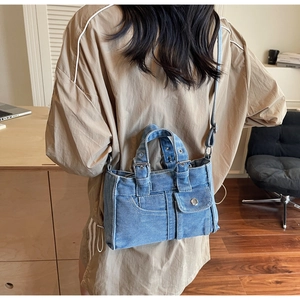 Blue denim tote bag with multi-pocket design shown on model for size perspective