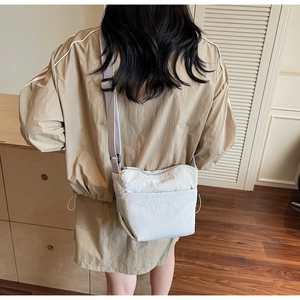 Détail du sac seau beige minimaliste avec texture plissée et large bandoulière réglable