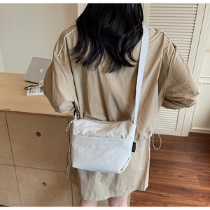 Détail du sac seau beige minimaliste avec tissu texturé et étiquette latérale