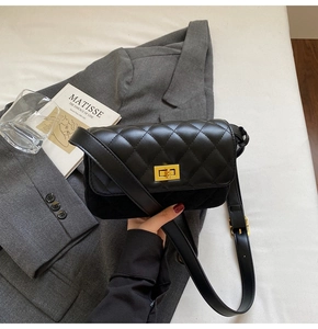 Close-up of black quilted shoulder bag with gold twist lock on a grey suit jacket