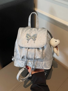 Silver metallic backpack with butterfly hardware and bear charm for summer commuting