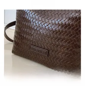 Close-up of dark brown woven texture handbag with CAHRES & HEKA brand leather label