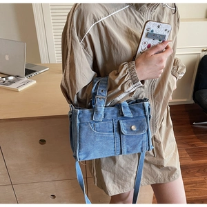 Detail showing the denim fabric texture and cargo pocket of this blue crossbody tote bag