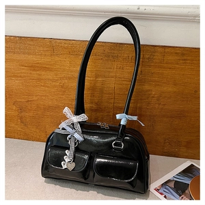 Detail of black patent leather shoulder bag with white lace bows and heart charm