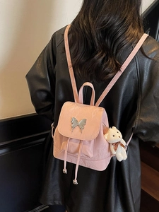 Pink faux leather backpack with silver butterfly buckle and plush bear charm on model