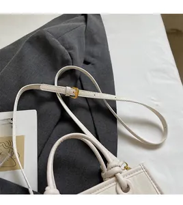 Détail de la bandoulière réglable avec boucle dorée sur un sac à main beige élégant