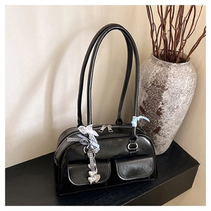 Detail of a black glossy shoulder bag featuring double front pockets and silver hardware