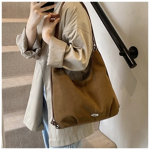 Close-up of brown suede tote bag featuring slim straps and silver oval metal buckle detail