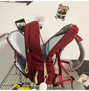 Detail of burgundy backpack main compartment with gray lining and mesh shoulder straps