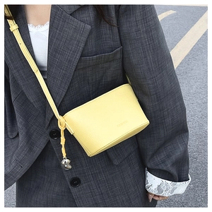Detail of yellow pebble leather crossbody bag with FASHION emboss and knot metal ball