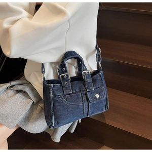 Detail of blue denim tote bag featuring dual front pockets and silver metal hardware
