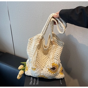 Detail of sunflower crochet straw tote bag with long tassels and woven handle design