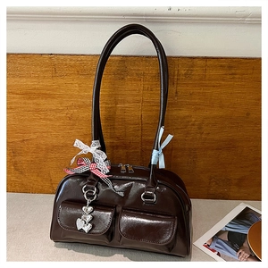 Detail of dark brown oil wax leather bag with silver heart charms and lace ribbons