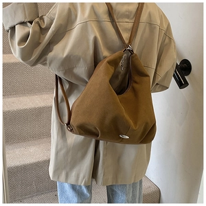Brown canvas multi-way backpack with elegant pleated bottom shown on a shoulder