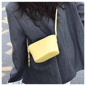 Detail of yellow leather crossbody bag with FASHION embossing and heart pendant