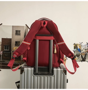 Detail of red travel backpack with luggage strap and reflective safety strips on straps