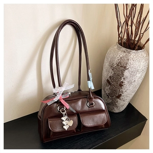 Macro detail of dark brown leather bowling bag with silver buckles and heart charms
