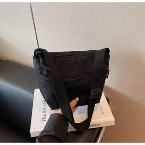 Détail du sac seau en nylon noir texturé avec bandoulière réglable et étiquette