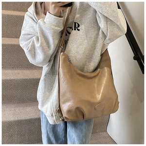 Detail view of light brown PU leather hobo bag showing metallic zipper and logo patch