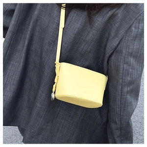 Close-up of yellow lychee leather crossbody bag with FASHION embossed logo on blazer
