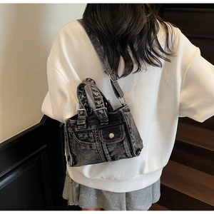 Detailed view of a street style vintage wash denim crossbody bag worn by a model