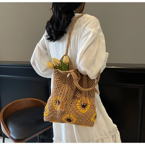 Close-up of handmade sunflower straw tote bag with woven fringe tassels and crochet details